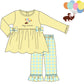 A children's two-piece set shown as a flat illustration on a white background. The set includes a pale yellow long-sleeve top with bow details and a scalloped hem, paired with light blue and yellow plaid pants with ruffled hems.