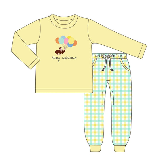 A children's set consisting of a pale yellow long-sleeve top with a balloon graphic and the words 'stay curious' and matching plaid pants in yellow and light blue, shown on a plain white background.